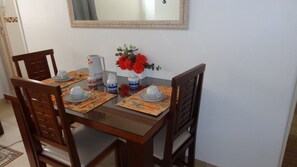 A dining area with a table for four, complete with comfortable chairs and a vase with flowers.