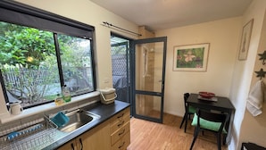 Cocina compacta con ventana, lavamanos y zona de comedor con mesa y sillas.