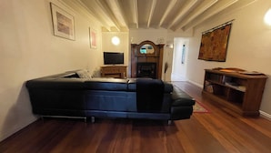 Una sala de estar con un sofá modular, televisor, chimenea y una estantería.