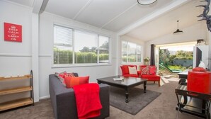 A living room with a grey sofa, red cushions, a coffee table, and a red grill. - The Abbey - Gorgeous Living In the Village (Point Wells)