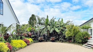 A garden with a gravel path leading to a white building. - The Abbey - Gorgeous Living In the Village (Point Wells)