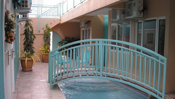 An indoor swimming pool with a turquoise bridge, potted plants, and a tiled floor. - Easy Walk To Store Bay, Pigeon Point, Restaurants & Entertainment (Crown Point)