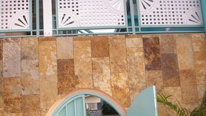 A light blue arched entrance with decorative metalwork, leading to a covered outdoor area with a stone wall backdrop. - Easy Walk To Store Bay, Pigeon Point, Restaurants & Entertainment (Crown Point)