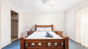 A bedroom with a wooden bed, two bedside tables, a ceiling fan, and a closet with a door open. - Home away from home - Close to the beach (GERRINGONG)