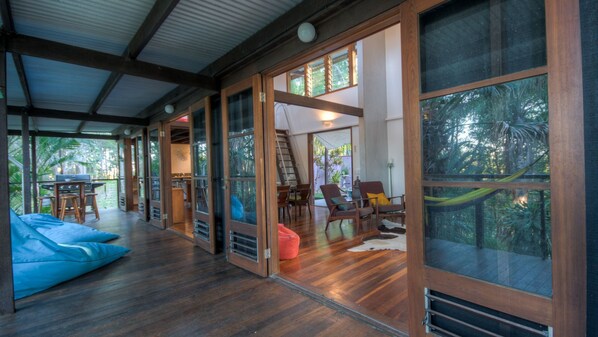 Relax in a spacious living area with a high ceiling and large windows offering views of the surrounding greenery.