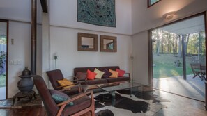Relax in this stylish living room with a glass coffee table, armchairs, and a cozy stove.