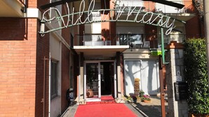 Villa Mart's entrance with a red carpet, a metal gate, and a sign above the door. - Hotel Villa Mary (Loano)