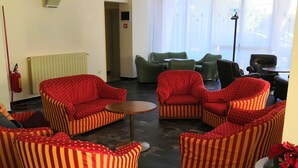 A hotel lobby with striped armchairs, a small round table, and a radiator. - Hotel Villa Mary (Loano)