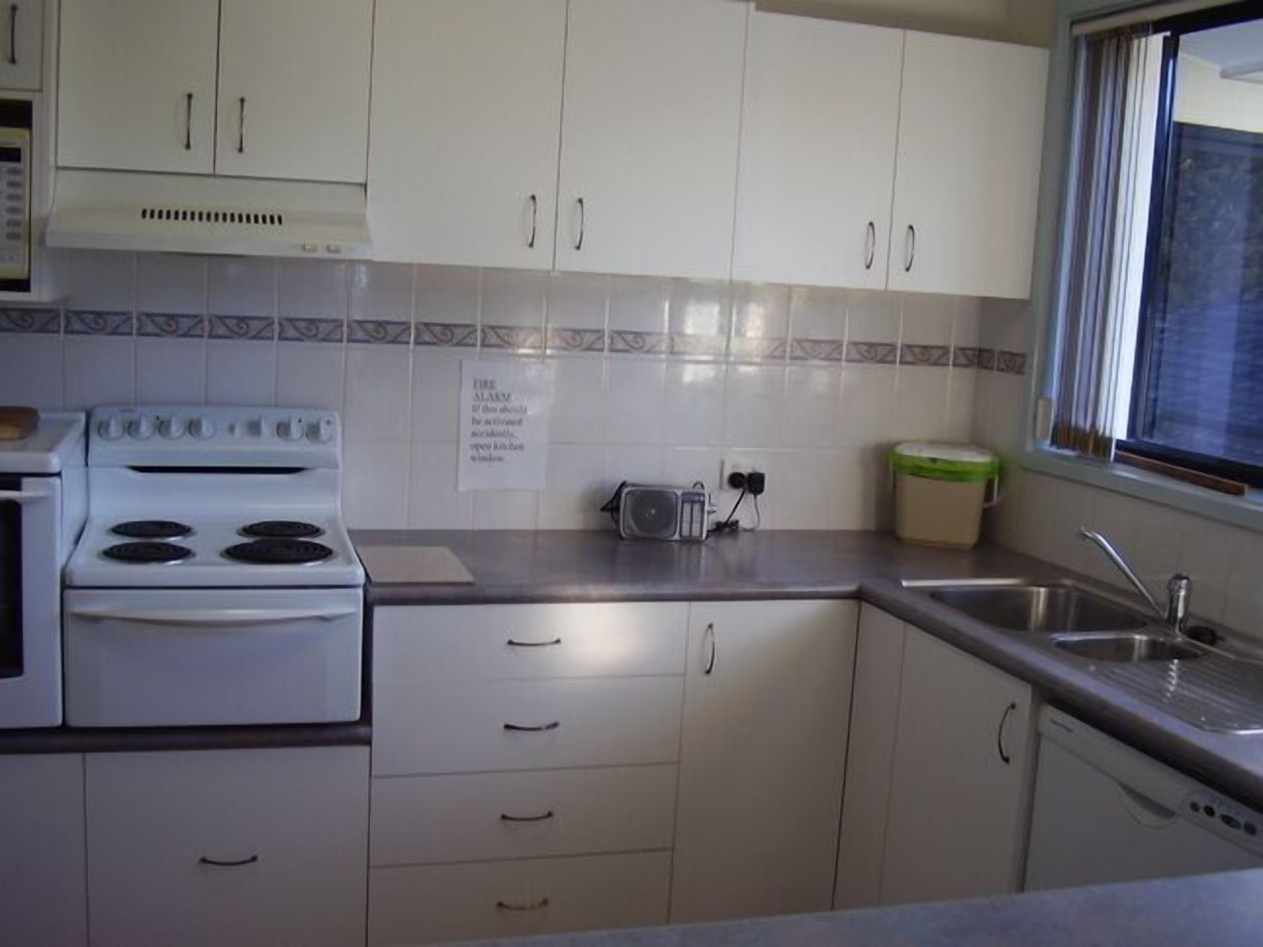 A kitchen with white cabinets, a stove, a toaster, and a sink.