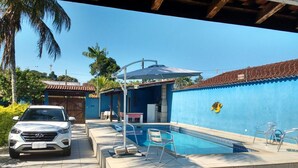 A swimming pool with lounge chairs, a covered area, and a car parked nearby. - House in Boracéia II with Pool, 3 Bedrooms (2 Suites), Billiard Table, 4 Bathrooms (São Sebastião)