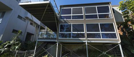 A multi-story building with a glass balcony and a staircase leading to the upper floors.