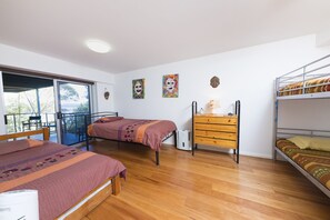 Quarto com duas camas, uma cômoda e varanda com uma cadeira.
