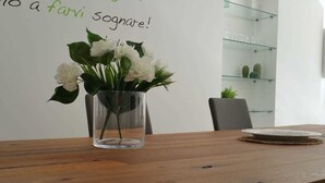 A wooden table with a clear glass vase containing white flowers. - Bed and breakfast Ledwars (Taviano)