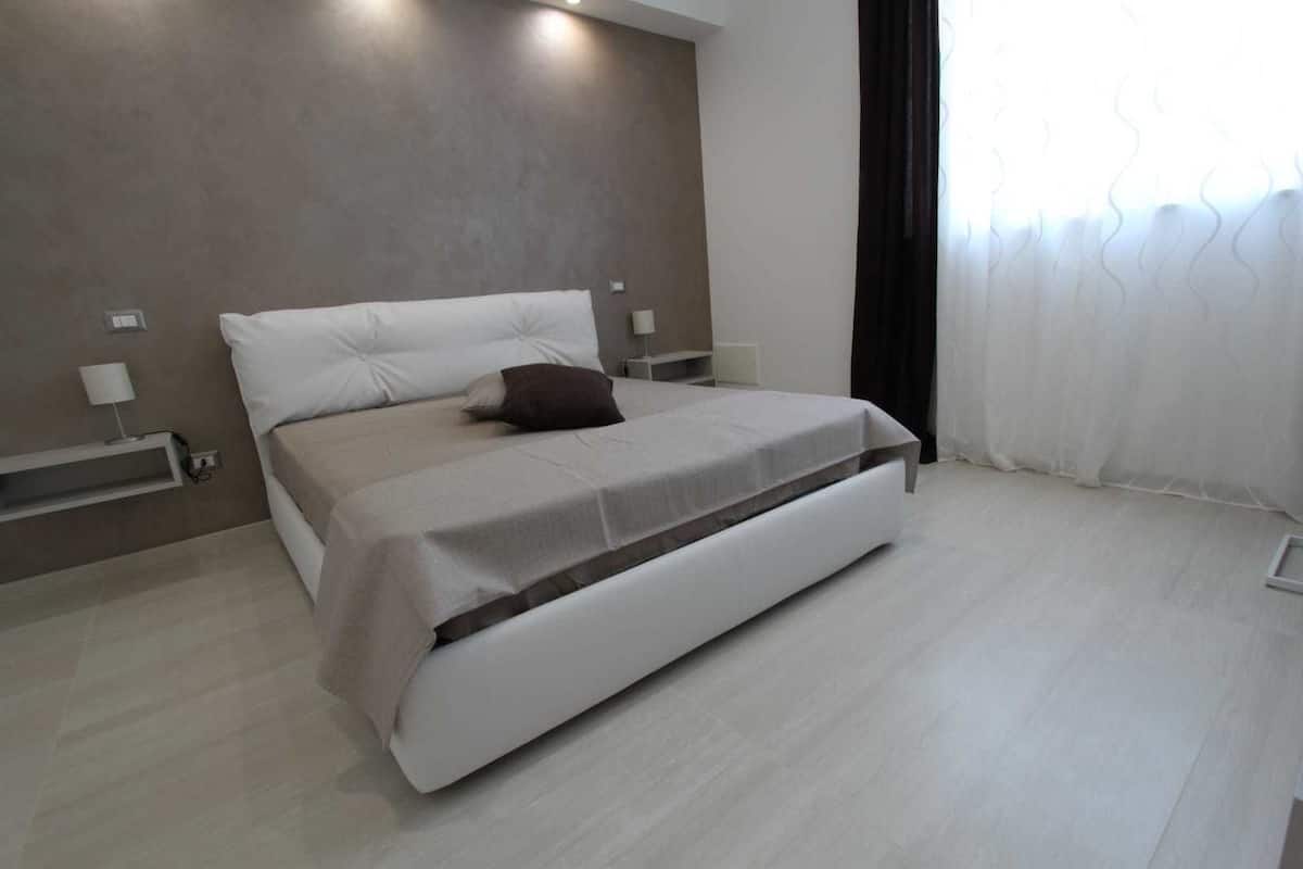 A modern bedroom with a large bed, a bedside table, and a nightstand.