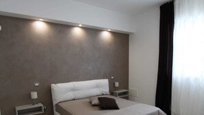 A modern bedroom with a large bed, bedside tables, and a built-in shelf. - Bed and breakfast Ledwars (Taviano)