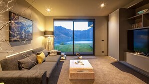 A modern living room with a large window, a sofa, a coffee table, and a television.