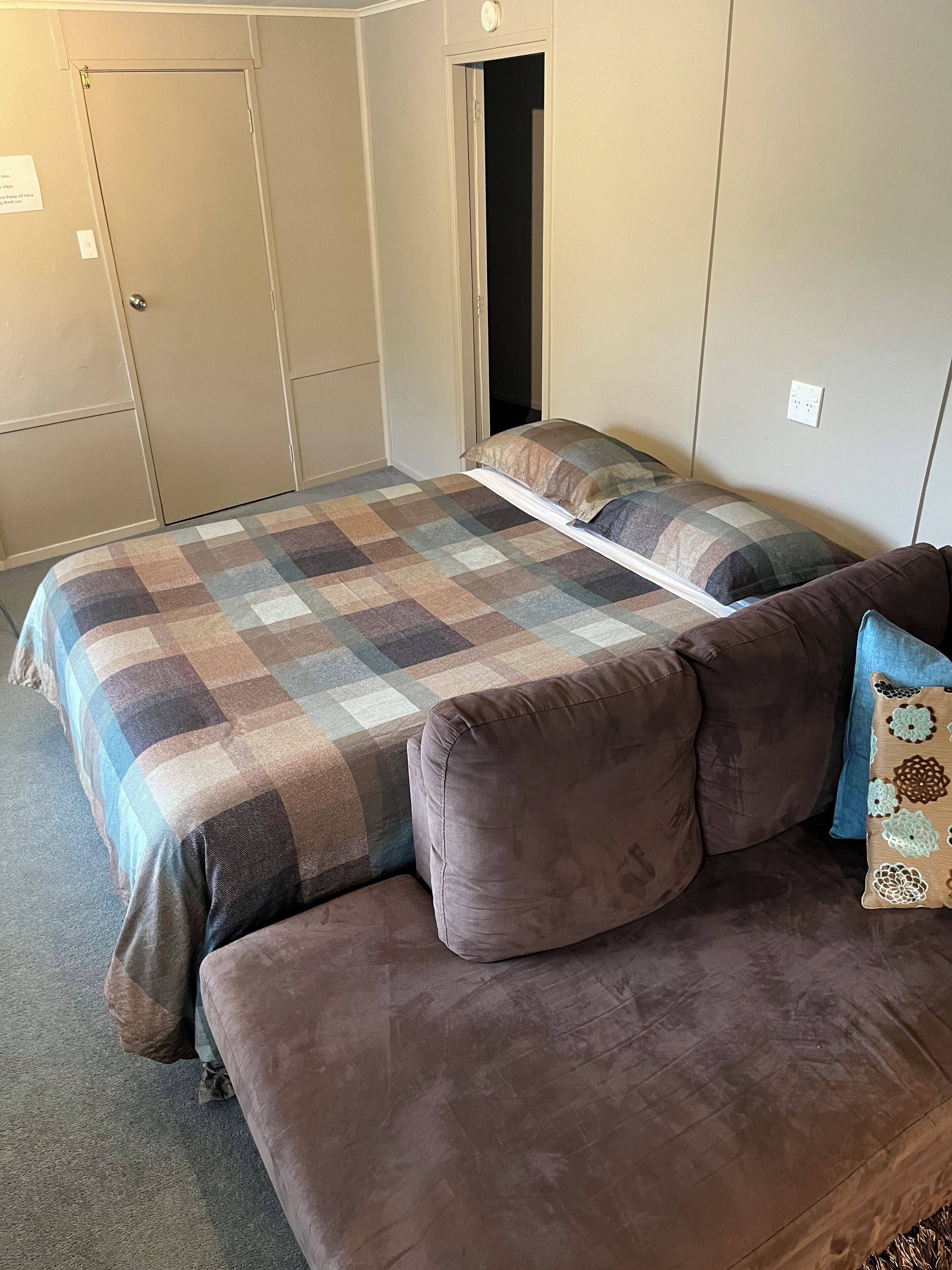 A room with two beds, a sofa, and a wardrobe.