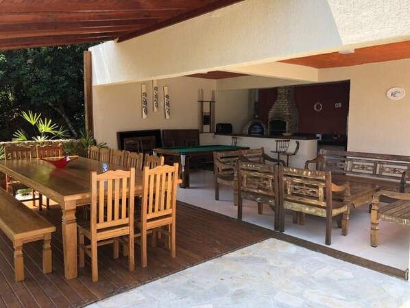 Un espacio de comedor al aire libre con mobiliario de madera y una mesa de billar.