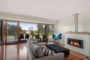 Una sala de estar moderna con un sofá, sillas, un televisor y una chimenea.