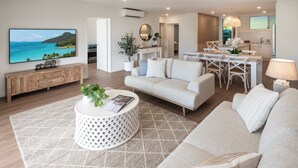 A modern living room with a large flat-screen TV, a round coffee table, and a sofa. - Lagoon 006 Hamilton Island by HamoRent (Hamilton Island)