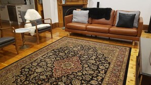 A living room with a brown leather sofa, a patterned rug, and a white chair.