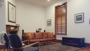 A living room with a brown leather sofa, a blue armchair, a patterned rug, and wooden flooring.