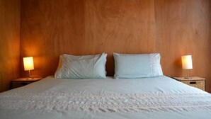 A hotel room with a large bed, two bedside lamps, and wooden paneling on the walls.
