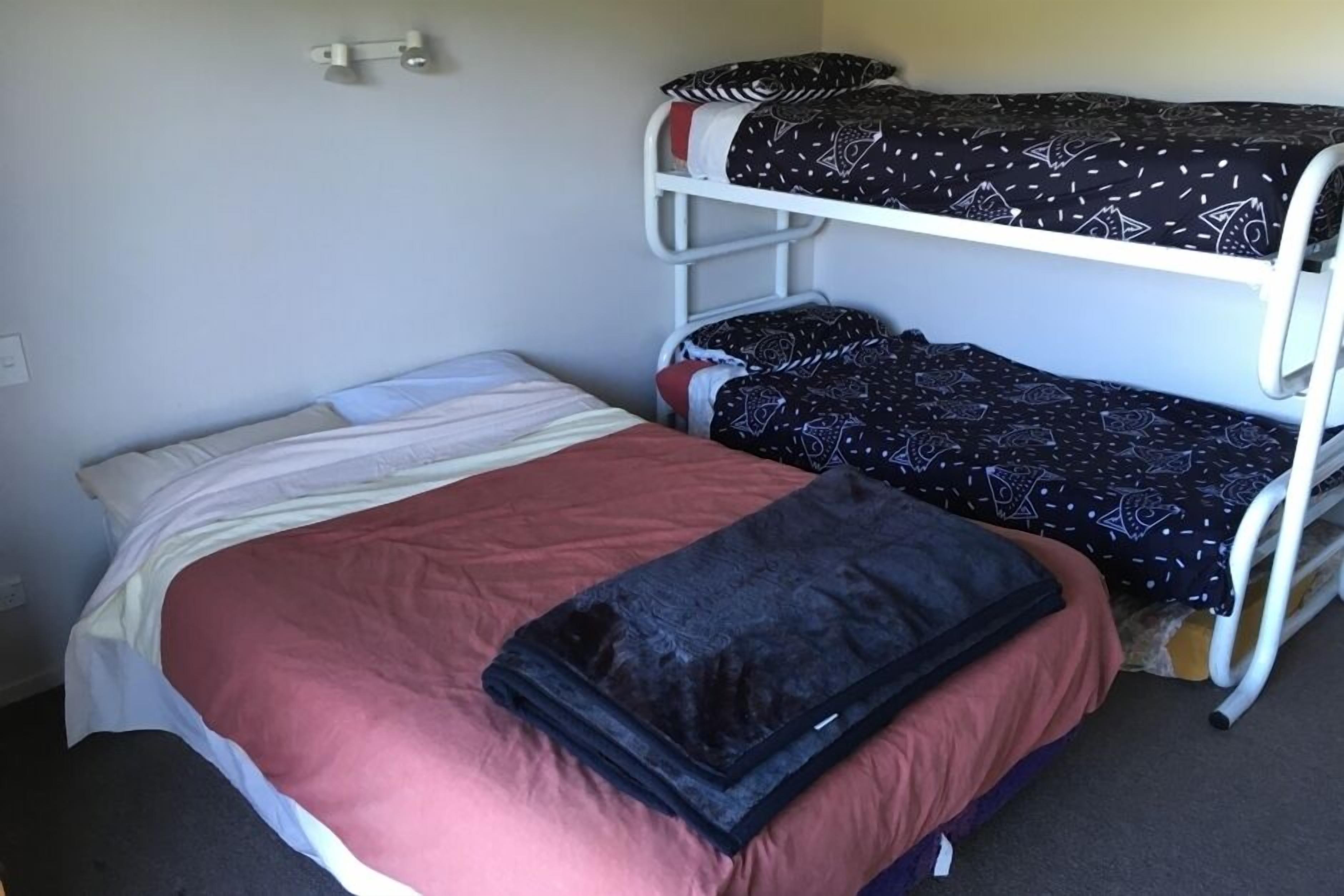 A bunk bed with a red and white bedspread, a black blanket, and patterned bedding.