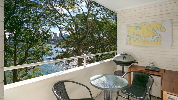Ein Balkon mit Blick auf ein Gewässer, eine Karte an der Wand und Gartenmöbel.