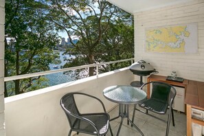 Een balkon met uitzicht op een waterpartij, een kaart aan de muur en tuinmeubilair.
