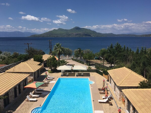 A pool area with a view of the sea and mountains. - Almyra Holiday Village (Istiaia-Aidipsos)