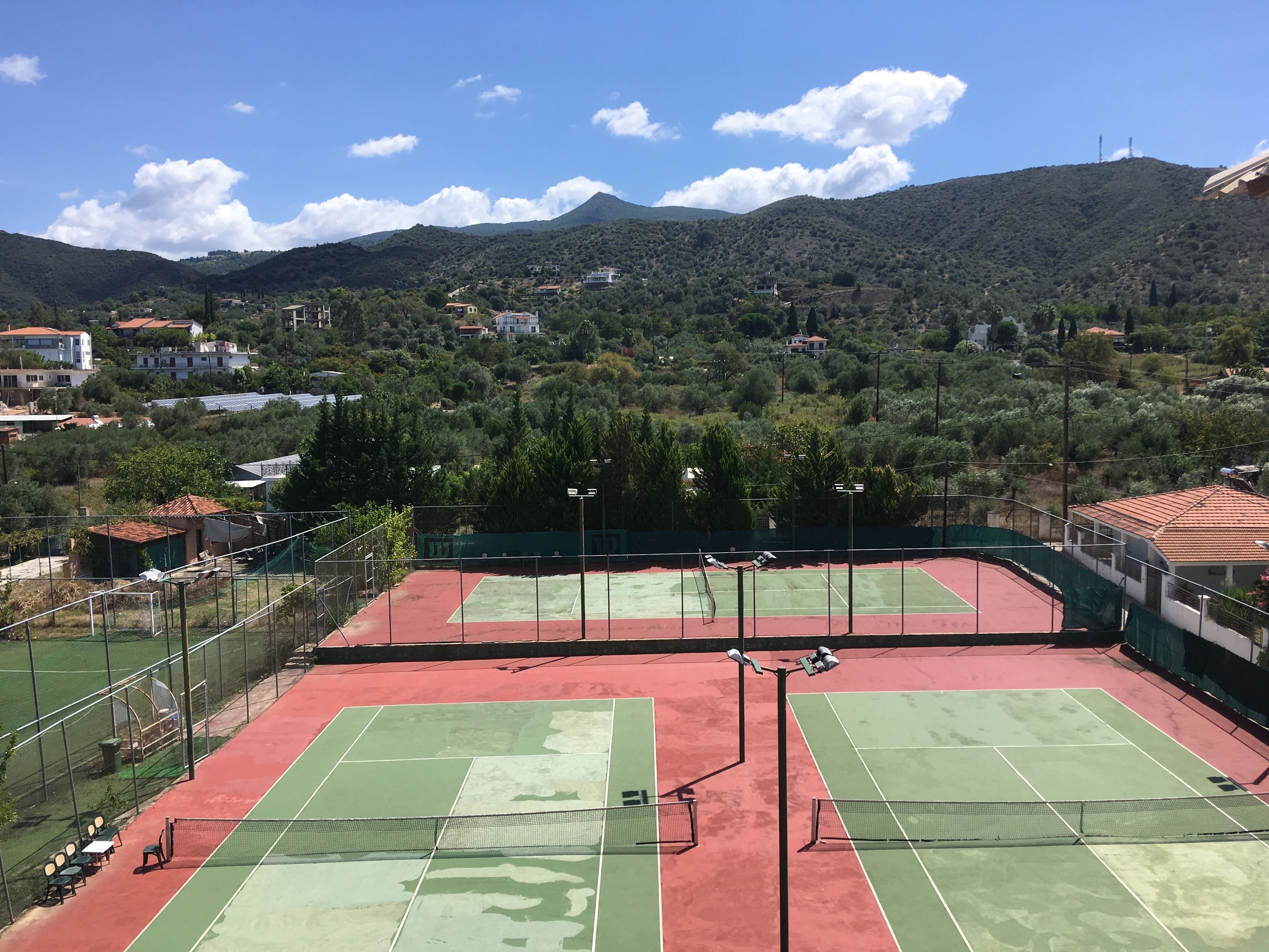 A tennis court with a net in the middle, surrounded by a fence.