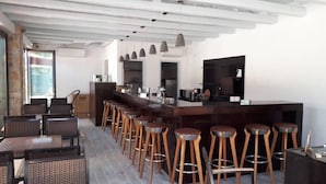 A modern kitchen with a bar area, wooden stools, and a dining area with wicker chairs. - Almyra Holiday Village (Istiaia-Aidipsos)