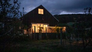 A rustic barn-style house with a large open front door and a small window at the top.
