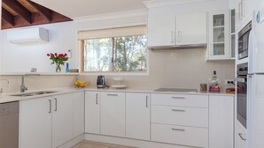 Een moderne keuken met witte kasten, een raam en een inbouwoven.