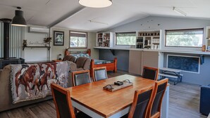 Amplio salón con mesa de comedor de madera, asientos cómodos y un gran ventanal que proporciona luz natural.