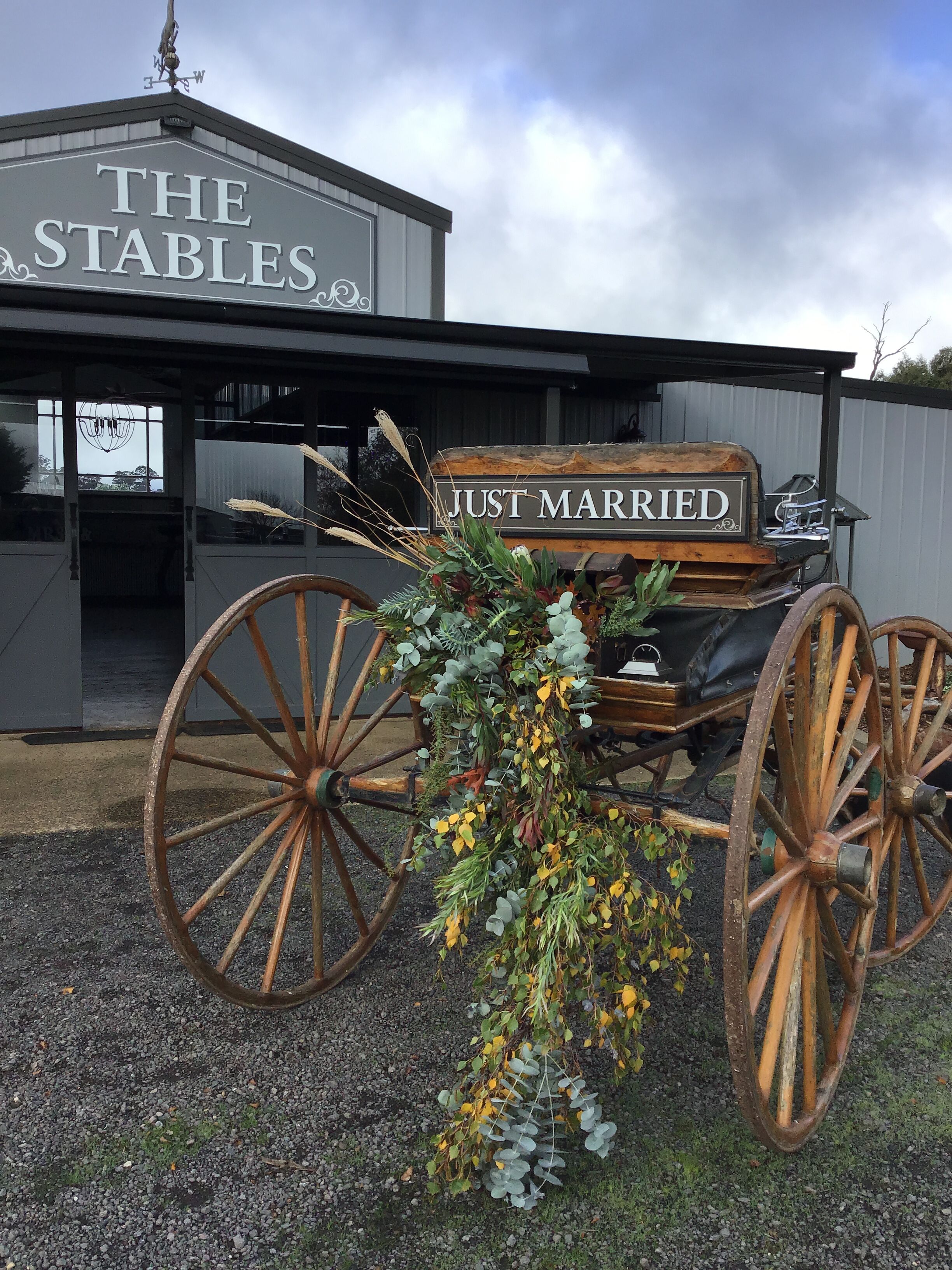 A wedding carriage with the inscription "JUST MARRIED" in front of a building labeled "THE STABLES."