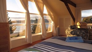 Een slaapkamer met een bed, een kaptafel, een stoel en uitzicht op een meer.