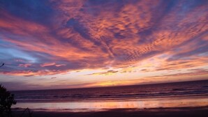 Een strand met een zonsondergang en wolken.
