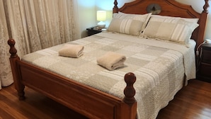 Una cama con dosel de madera, con colcha acolchada y dos toallas dobladas.