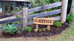 Un letrero de madera con el nombre "KYVALE" frente a una valla de madera rústica.
