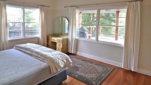 A bedroom with a bed, a dresser, a mirror, and a window with curtains. - 6 Broome Street, Mallacoota (Mallacoota)