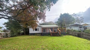 A residential property with a covered porch, a staircase leading to a deck, and a fenced backyard. - 6 Broome Street, Mallacoota (Mallacoota)