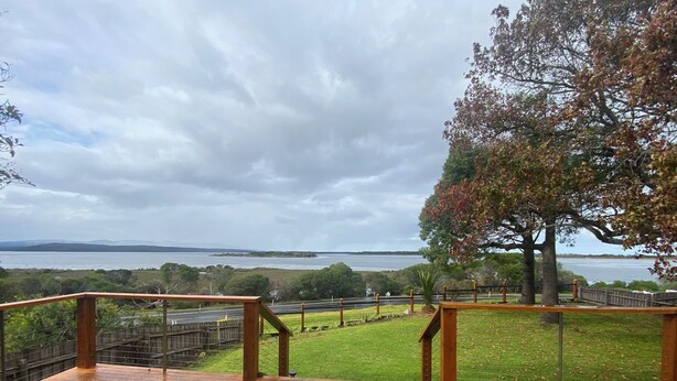 A wooden deck with a view of a lake and distant mountains. - 6 Broome Street, Mallacoota (Mallacoota)