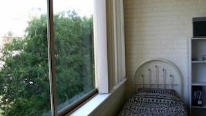 A bedroom with a window, a patterned bedspread, and a brick wall. - B6 Walk to UWA close to SCGH & CBD (Crawley)