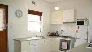 A kitchen with white cabinets, a stove, a microwave, and a sink. - B6 Walk to UWA close to SCGH & CBD (Crawley)