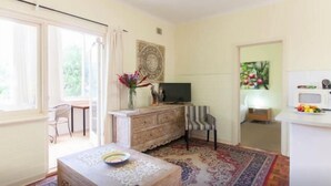 A room with a wooden table, a television, a patterned rug, and a window with curtains.