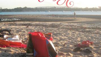 A beach with a tent, a bottle, and a bag on the sand.