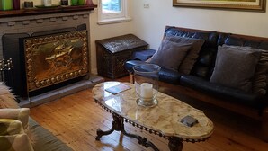 A living room with a sofa, a coffee table, a fireplace, a chandelier, and a painting on the wall.