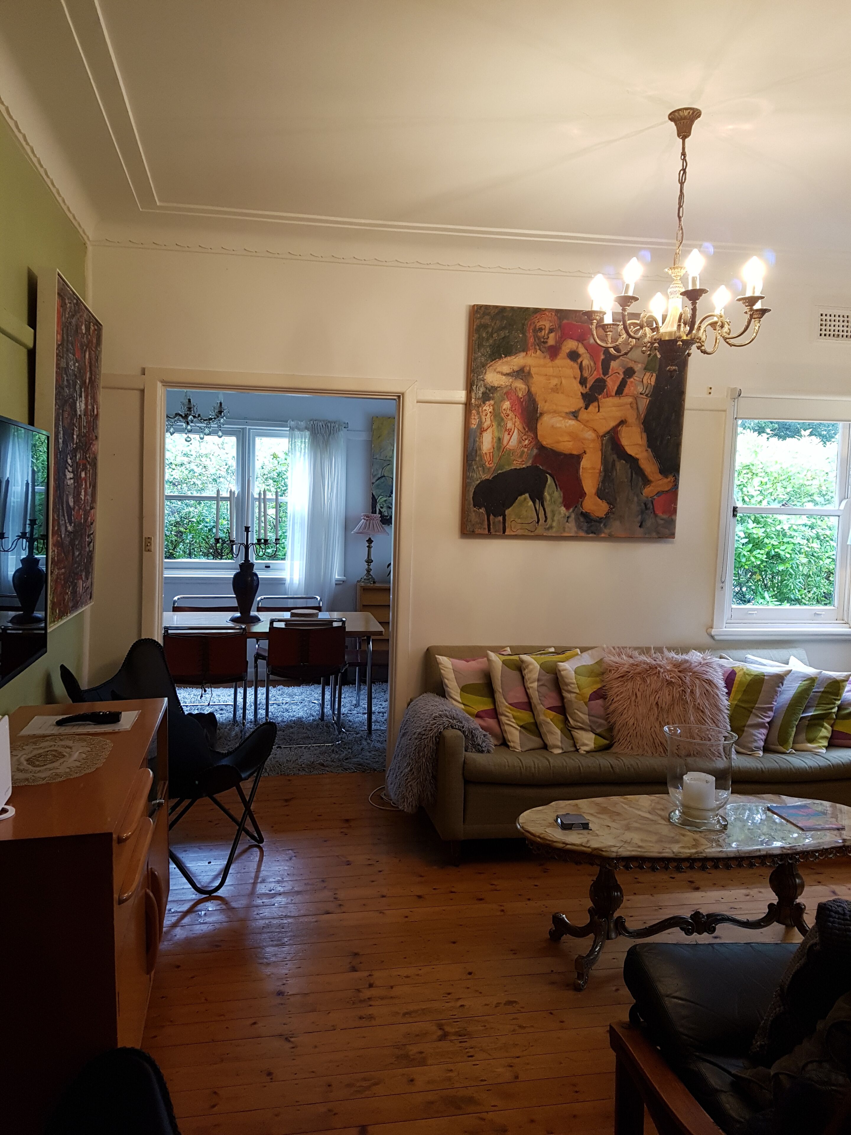 A living room with a sofa, a dining area, and a painting on the wall.